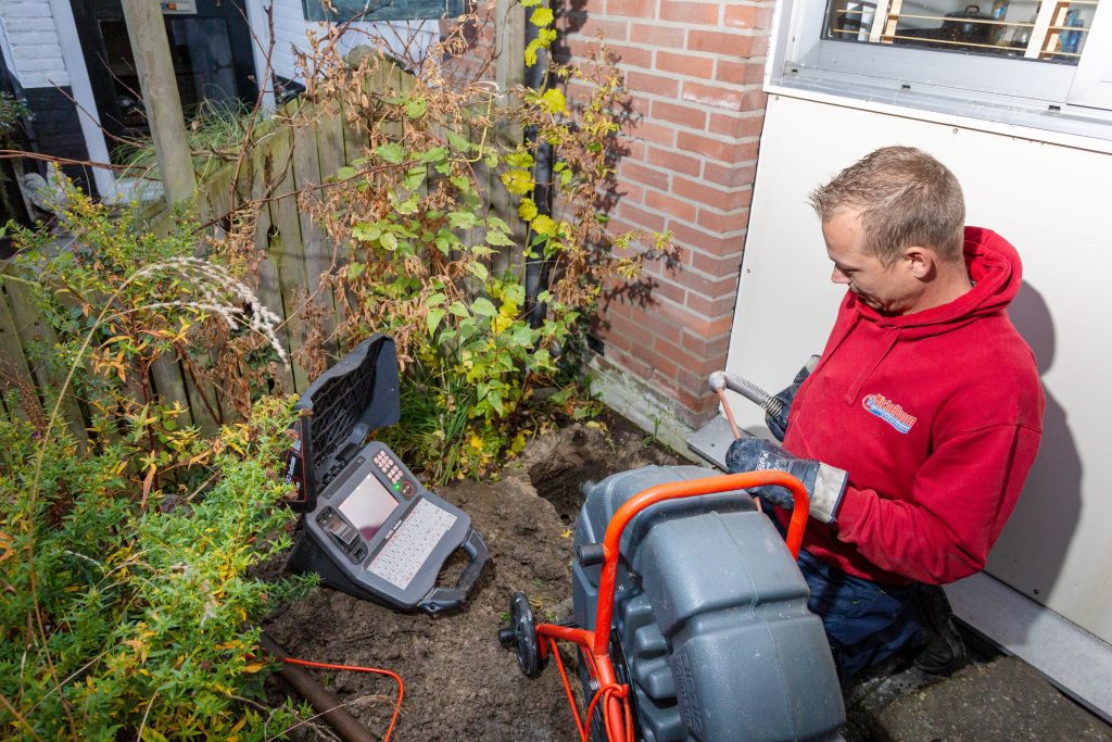 Medewerker van ontstopt Michel Doorn ontstopt regenpijp onder de grond