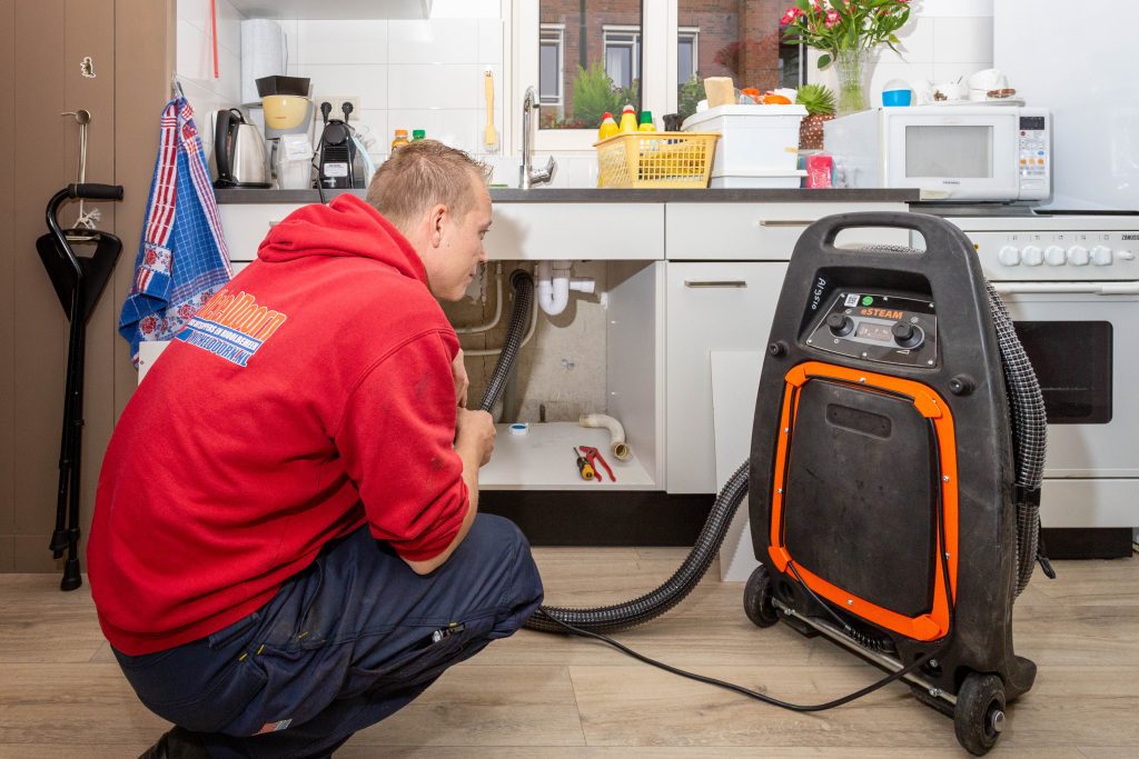 Een ontstopper van Michel Doorn is leidingen aan het reinigen met een machine